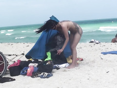 Tattooed brunette gets naked on the beach
