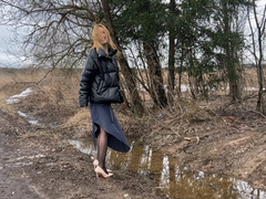girl in high-heeled shoes walks along a wet and dirty road, dirtying her shoes and stockingsR